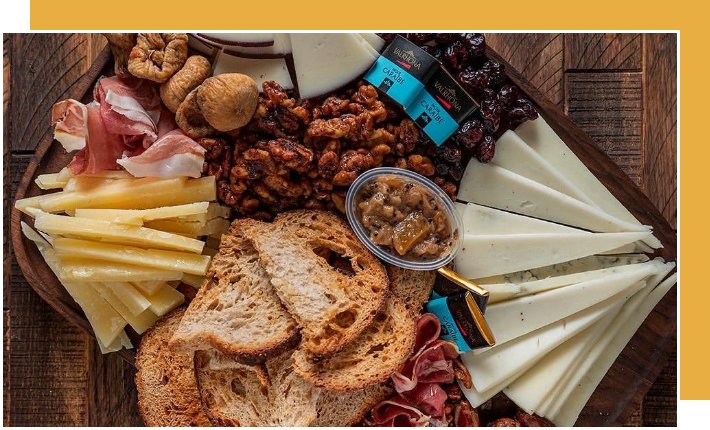A platter of cheese and meats on a wooden table.